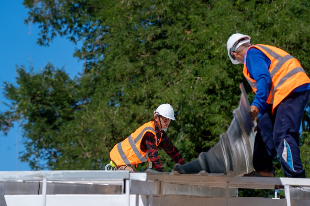 Construction workers laying single-ply membrane